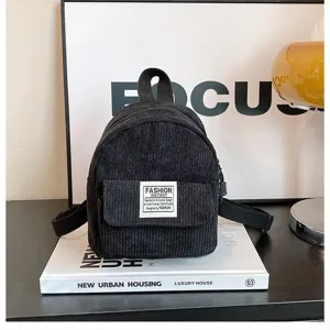 Detailed view of black corduroy mini backpack showing textured fabric and fashion label