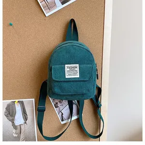 A detailed view of a stylish teal corduroy mini backpack displayed on a creative corkboard.