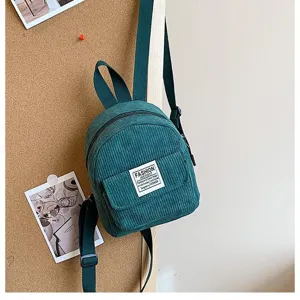 Detail of a dark green corduroy mini backpack with front pocket in a lifestyle setting