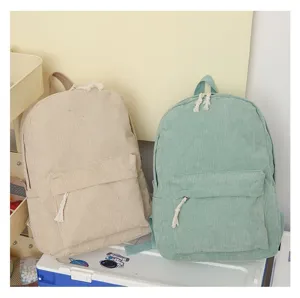 Primer plano de mochilas de pana minimalistas en beige y verde menta con tiradores de borla