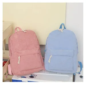 Par de mochilas de pana suaves en rosa y azul claro sobre una caja de almacenamiento