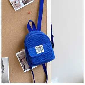 Stylish blue corduroy mini backpack hanging on a cork board for outdoor casual travel