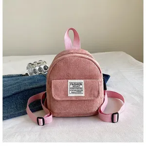 Compact pink corduroy mini backpack featuring an artistic fashion label on white fabric