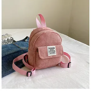 Close-up view of a pink corduroy mini backpack showing its soft texture and patch