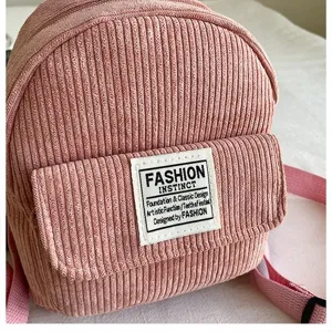 Detailed close-up view of a pink corduroy mini backpack featuring a stylish text patch