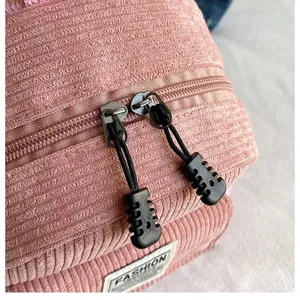 Close-up macro view showing pink corduroy texture and dual zippers of the backpack