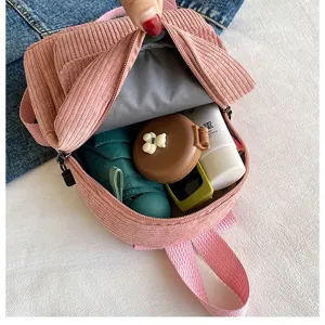 Detail view of pink corduroy mini backpack showing interior capacity and lining