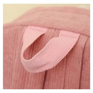 Primer plano de una mochila de pana rosa que muestra el asa superior y las costuras