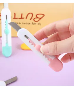 Primer plano del uso de un mini cúter rosa y blanco para tareas de corte de papel manual
