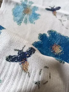 Close-up of Bohemian floral and bee print on a soft knit sweater fabric texture.