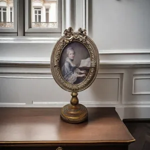Vintage European carved gold oval photo frame with classical portrait on a wooden vanity