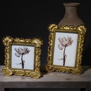 Close-up detail of ornate antique gold picture frames featuring intricate relief design on a rustic wood surface.
