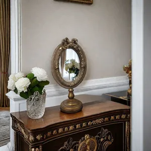 European vintage carved oval photo frame with aged gold finish on an elegant vanity
