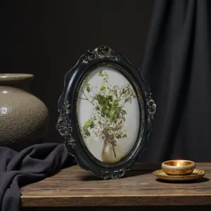 Primer plano de un marco de fotos ovalado de resina negra vintage con tallas florales talladas