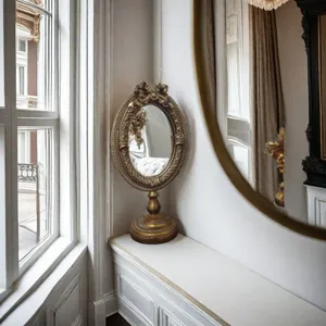 Intricate vintage French gold carved photo frame displayed on a vanity near a window.