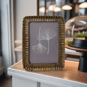Détail en gros plan du cadre photo vintage en résine dorée avec un élégant motif de ginkgo.