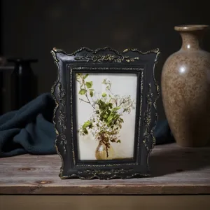 Primer plano de un marco de fotos vintage de resina negra con tallas florales doradas