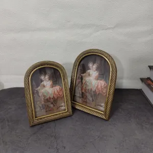 Detail view of two vintage European arched gold resin photo frames on table