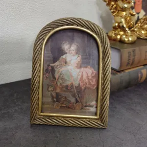 Detail of vintage European arched gold resin photo frame with twisted rope edge texture.
