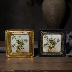 Pair of vintage European-style embossed picture frames displayed on a rustic wooden table