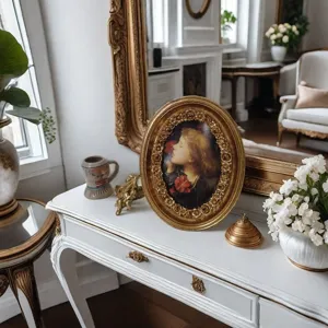 Cornice ovale vintage in resina dorata ornata su un classico tavolo da toeletta francese bianco