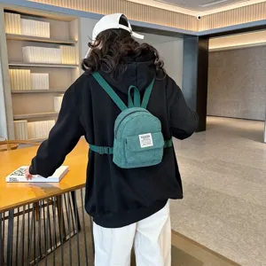 Stylish green corduroy mini backpack for women shown in a modern lifestyle setting