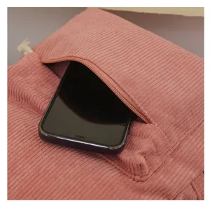 Detalle de mochila de pana rosa que muestra un bolsillo frontal para teléfono