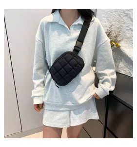 Detalle de una bolsa de pecho acolchada negra llevada cruzada con ropa informal