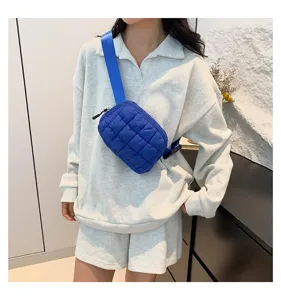 Riñonera acolchada azul usada como bolso de pecho cruzado de moda en una modelo femenina.
