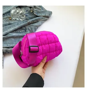 Primer plano de un bolso de pecho acolchado rosa vibrante sostenido para mostrar su textura