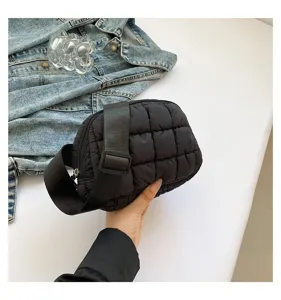Primer plano de un bolso de pecho negro acolchado con textura suave y tamaño de mano