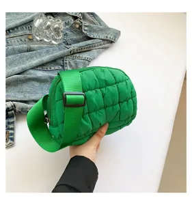 Primer plano de un bolso de pecho acolchado verde vibrante para mujer en un entorno casual.