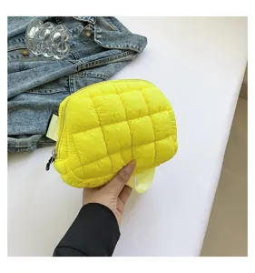 Primer plano de un bolso de pecho acolchado amarillo brillante sostenido en la mano.