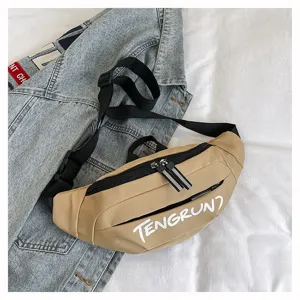 Detailansicht einer khakifarbenen Bauchtasche mit weißer Aufschrift auf Jeanshintergrund