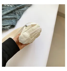 Primer plano de un mini bolso de pecho acolchado blanco con textura suave y cremallera.