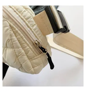 Detalle de cerca de la textura acolchada y la cremallera de la riñonera de moda crema