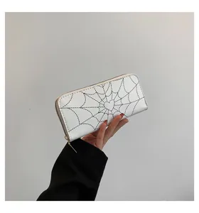 Close-up of white women's long wallet featuring black spiderweb and heart print