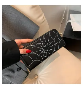 Detail view of a black long zipper wallet for women with white spiderweb heart print