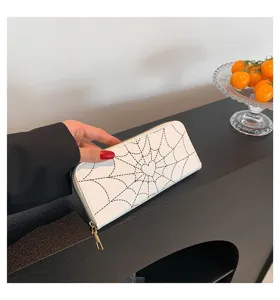Close-up detail of white women's long wallet featuring black spider web stitch print