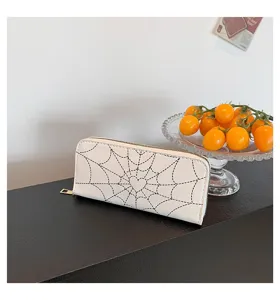 Detailed view of white women's long wallet featuring a black spider web print