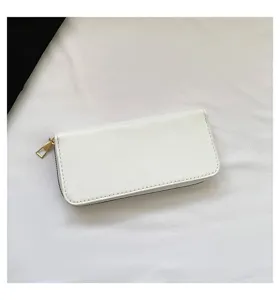 Detail view of a minimalist white faux leather long wallet with gold-tone zipper pull