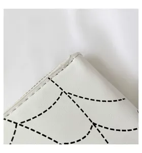 Close-up of spider web pattern and stitching on a white faux leather long wallet.