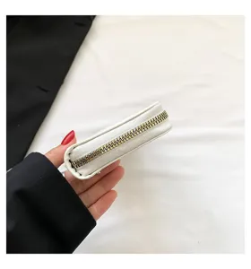 Side view detail of a white women's clutch wallet showing smooth gold zipper closure.