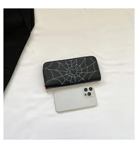 Close-up of a long black wallet with spider web print next to a smartphone for scale reference