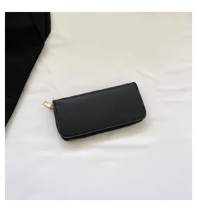 Plain black women's long zipper wallet with gold-tone hardware in a minimalist view