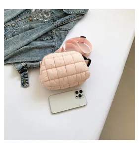 Detalle de la mini riñonera rosa acolchada en superficie blanca con chaqueta denim