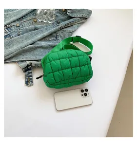 Bolso bandolera acolchado verde junto a un smartphone para comparar el tamaño real.