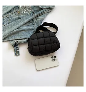 Bolso de pecho acolchado negro de moda con un smartphone para referencia de tamaño.