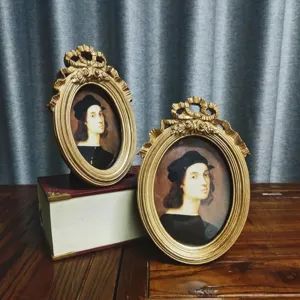 Two vintage European court-style resin photo frames on a wooden table with antique books