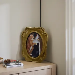 Marco de fotos vintage de resina dorada con tallas y retrato de gato sobre mueble